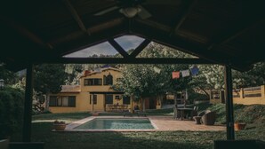 Un espacio al aire libre cubierto con piscina, asientos y un edificio al fondo.