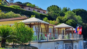 Eine Dachterrasse mit Sitzgelegenheiten im Freien, einer Pergola und Flaggen.