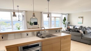 A modern kitchen with a built-in oven and a sink, wooden cabinets, and pendant lighting.
