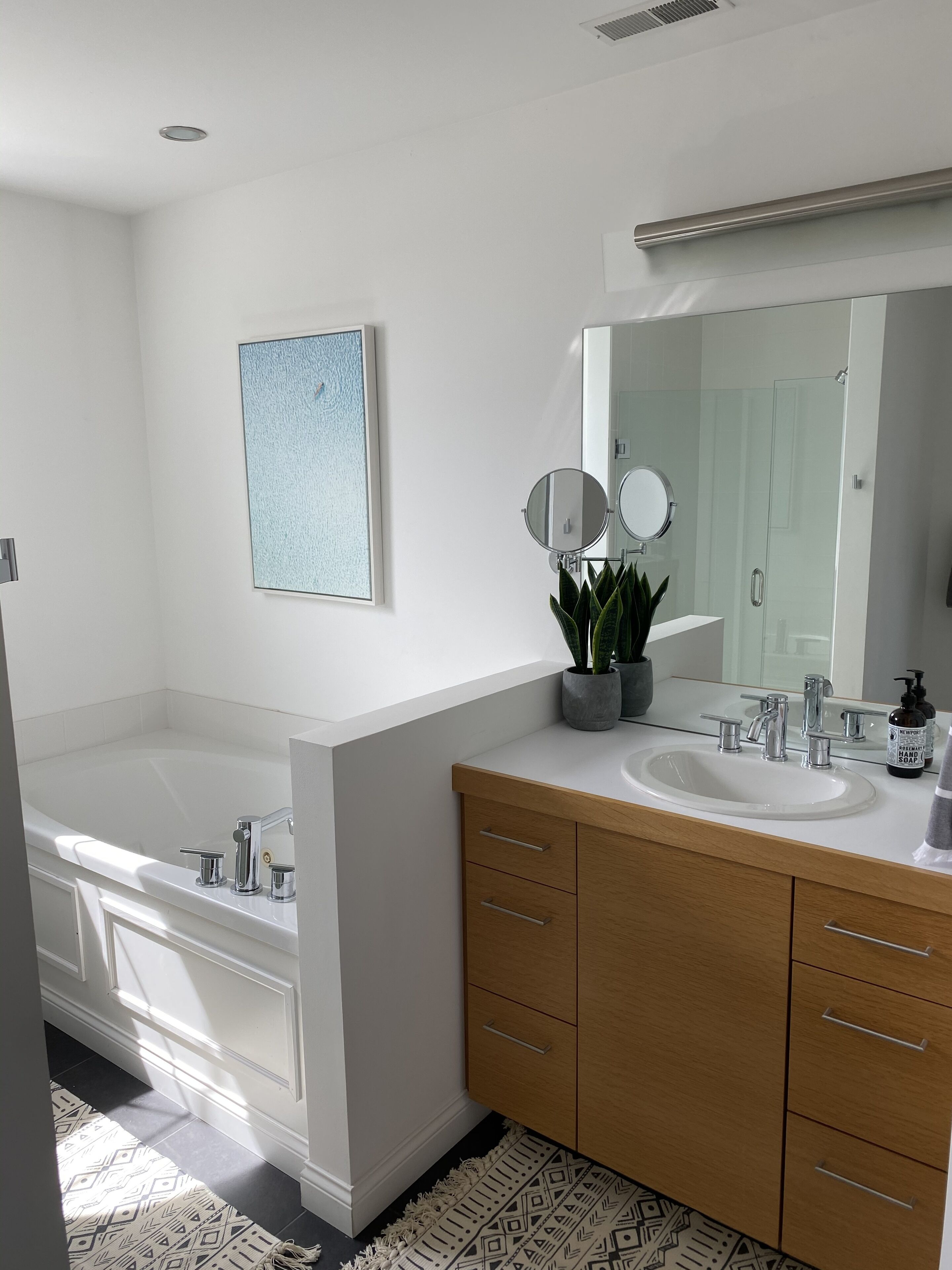 Une salle de bain moderne avec une baignoire, un lavabo avec un miroir et des meubles en bois.