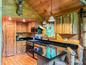 Una cocina rústica con armarios de madera, una estufa y una cabeza de venado colgada.