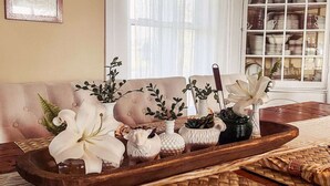 A cozy living room with a wooden tray holding decorative items, a cushioned sofa, and a window with curtains. - The ultimate cottagecore experience in a serene country setting overlooking USA's #1 State Park (Perry)