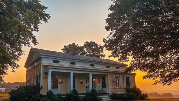A two-story house with a porch, surrounded by trees and a grassy lawn. - The ultimate cottagecore experience in a serene country setting overlooking USA's #1 State Park (Perry)