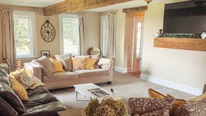 A cozy living room with a large sofa, a smaller couch, and a coffee table. There is a fireplace with a mantel above the sofa, and a clock on the wall. - The ultimate cottagecore experience in a serene country setting overlooking USA's #1 State Park (Perry)