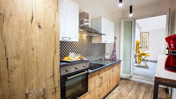 Une cuisine moderne avec des meubles en bois, une hotte de cuisine en acier inoxydable et un dosseret carrelé.