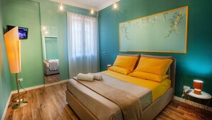 Une chambre à coucher avec un lit, une table de chevet et un téléviseur fixé au mur.