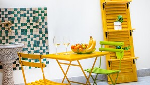 Un petit coin repas avec une table, des chaises et un saladier rempli de fruits.