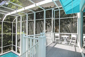 Una terraza techada al aire libre con piscina, barandillas blancas y una mesa con sillas.