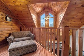 A wooden interior with a sloped ceiling, a sofa, and a window with a view. - Cozy Mountain Retreat w Pools &Free Attraction Tix (Pigeon Forge)