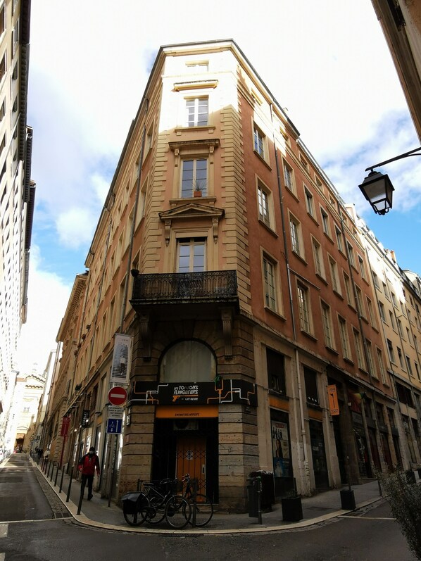 A corner building with a sign for 'Les Tom's Flingueurs' and a no entry sign.