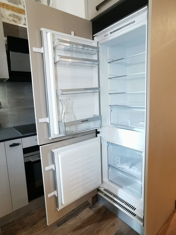 A modern kitchen with a built-in Siemens refrigerator, a black countertop, and wooden flooring. - Air-conditioned apartment in the city center, top floor (69001 - LYON 01)