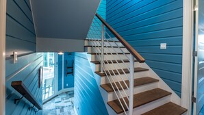 Een trap met blauwe wanden en houten treden, leidend naar een deur.