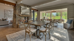 Un vaste espace dédié à la salle à manger, agrémenté d’une cheminée en pierre, d’une table à manger en bois et de sièges confortables.