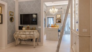 Un amplio salón con una televisión de pantalla plana grande, una consola decorativa y un candelabro.