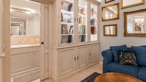 Una habitación con un armario empotrado con puertas de vidrio, un sofá azul y una mesa de centro.