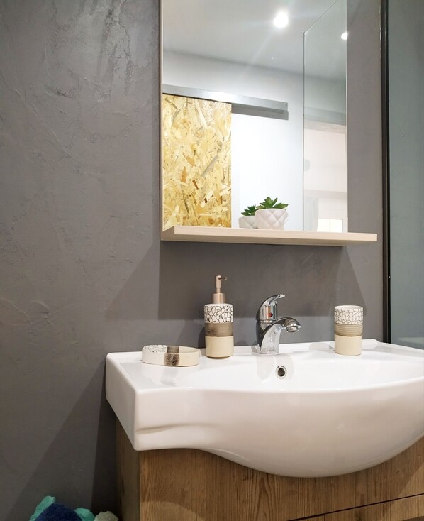 A bathroom with a white sink, a mirror above it, and a wooden cabinet below.