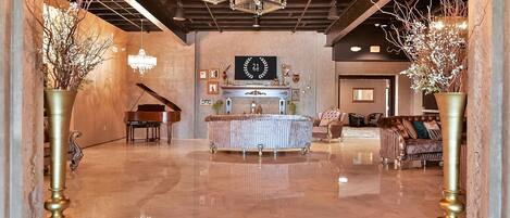 A spacious lobby with a grand chandelier, a piano, a fireplace, and elegant furniture.