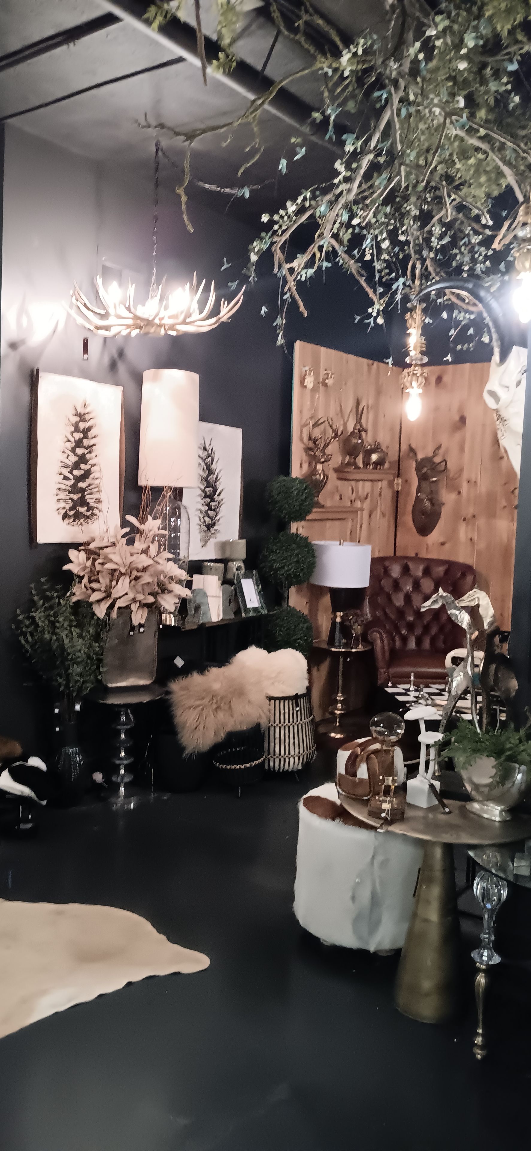 Una habitación con piso oscuro, un felpudo de piel, una pared de madera con cabeza de ciervo y un candelabro.