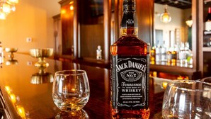 A bottle of Jack Daniel's Tennessee Sour Mash Whiskey on a bar counter with two glasses. - Hotel 21 & Co. (Gering)