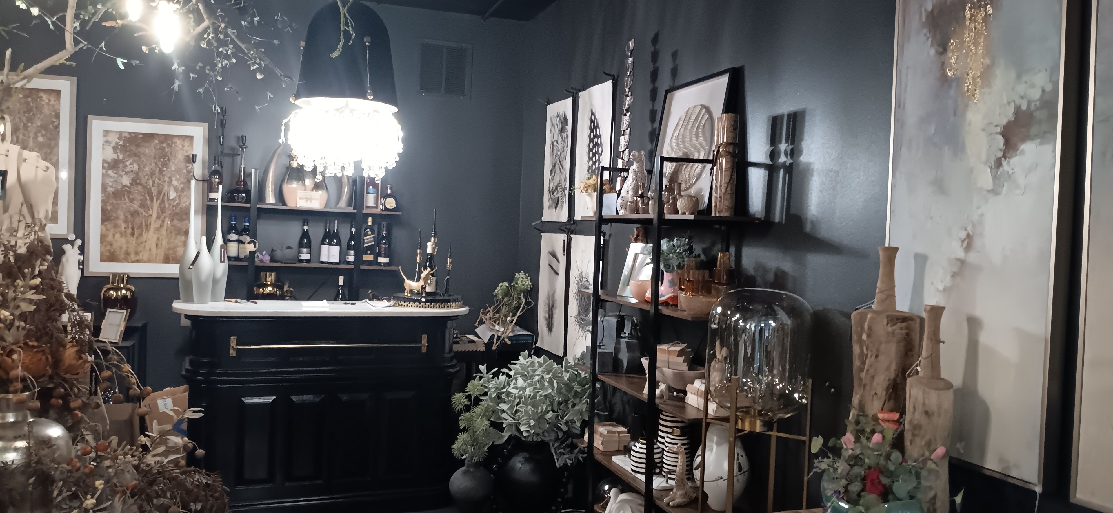 A well-organized bar area with shelves of bottles, a chandelier, and various decorative items.