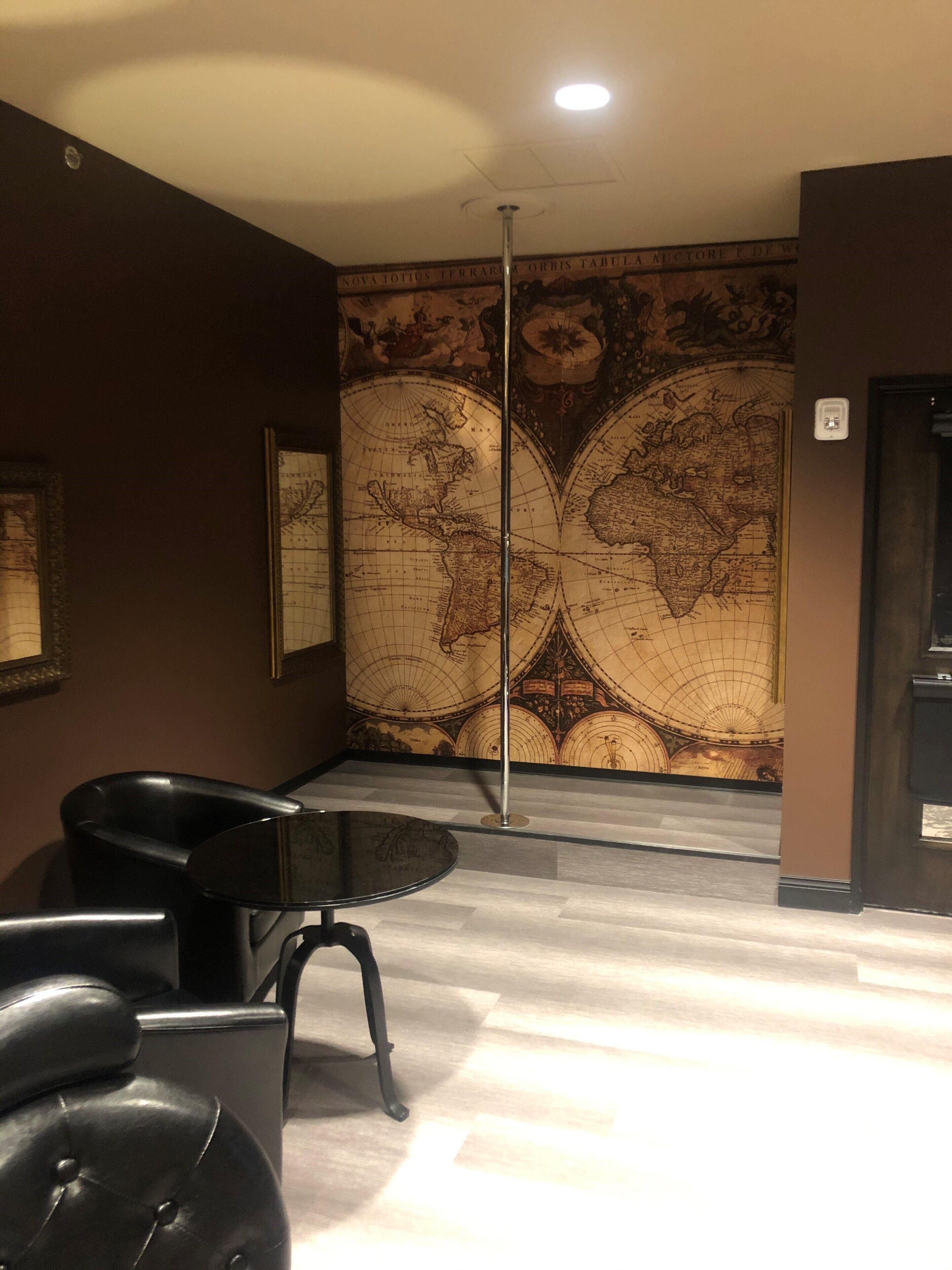 Una habitación con un gran mural de un mapa mundial, un sillón de cuero negro y una mesa de cristal.