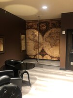 Una habitación con un gran mural de un mapa mundial, un sillón de cuero negro y una mesa de cristal.