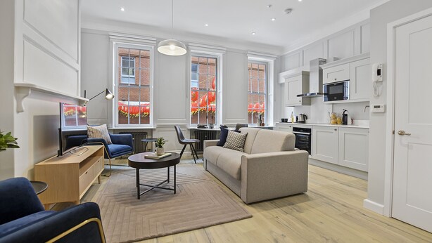 A modern living room with a sofa, a coffee table, and a dining area. - Gerrard Place by Aeria Apartments (London)