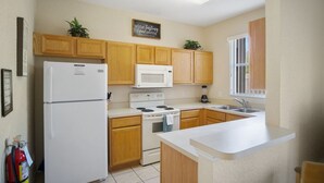 A kitchen with wooden cabinets, a white refrigerator, a stove, a microwave, and a sink. - 3BR Family Resort Townhouse - Lazy River & Water Slide - Disney 15 Min (Davenport)