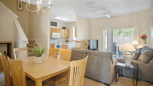 A spacious living area with a dining table, chairs, a sofa, and a TV. - 3BR Family Resort Townhouse - Lazy River & Water Slide - Disney 15 Min (Davenport)