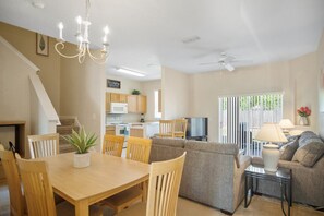 Un salón amplio con una mesa de comedor, sillas, un sofá y un televisor.