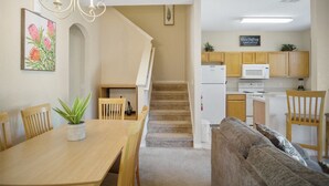 A modern kitchen with wooden cabinets, a microwave, and a dining area with a table and chairs. - 3BR Family Resort Townhouse - Lazy River & Water Slide - Disney 15 Min (Davenport)