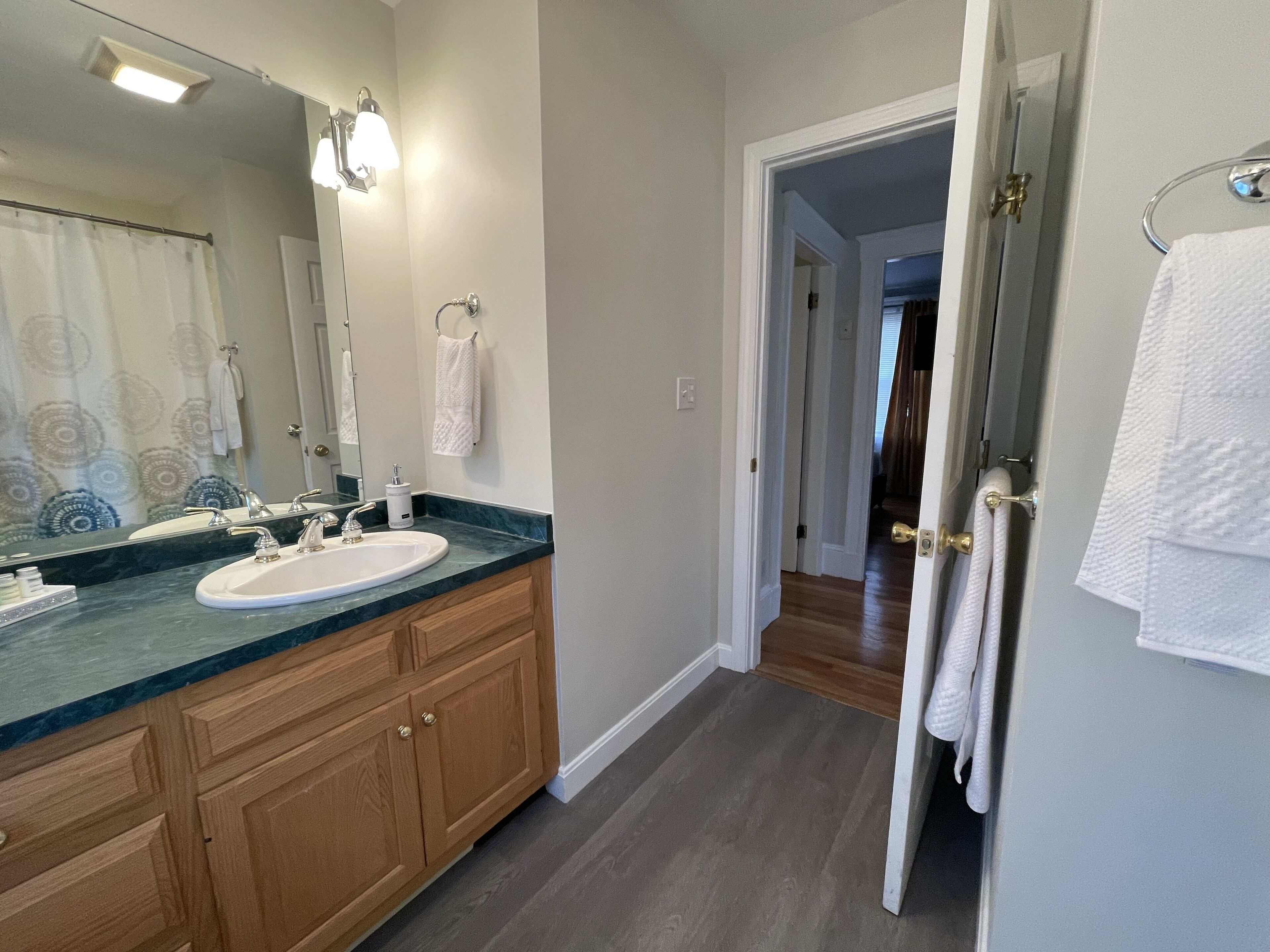 A bathroom with a double sink, wooden cabinets, a large mirror, and a towel rack.