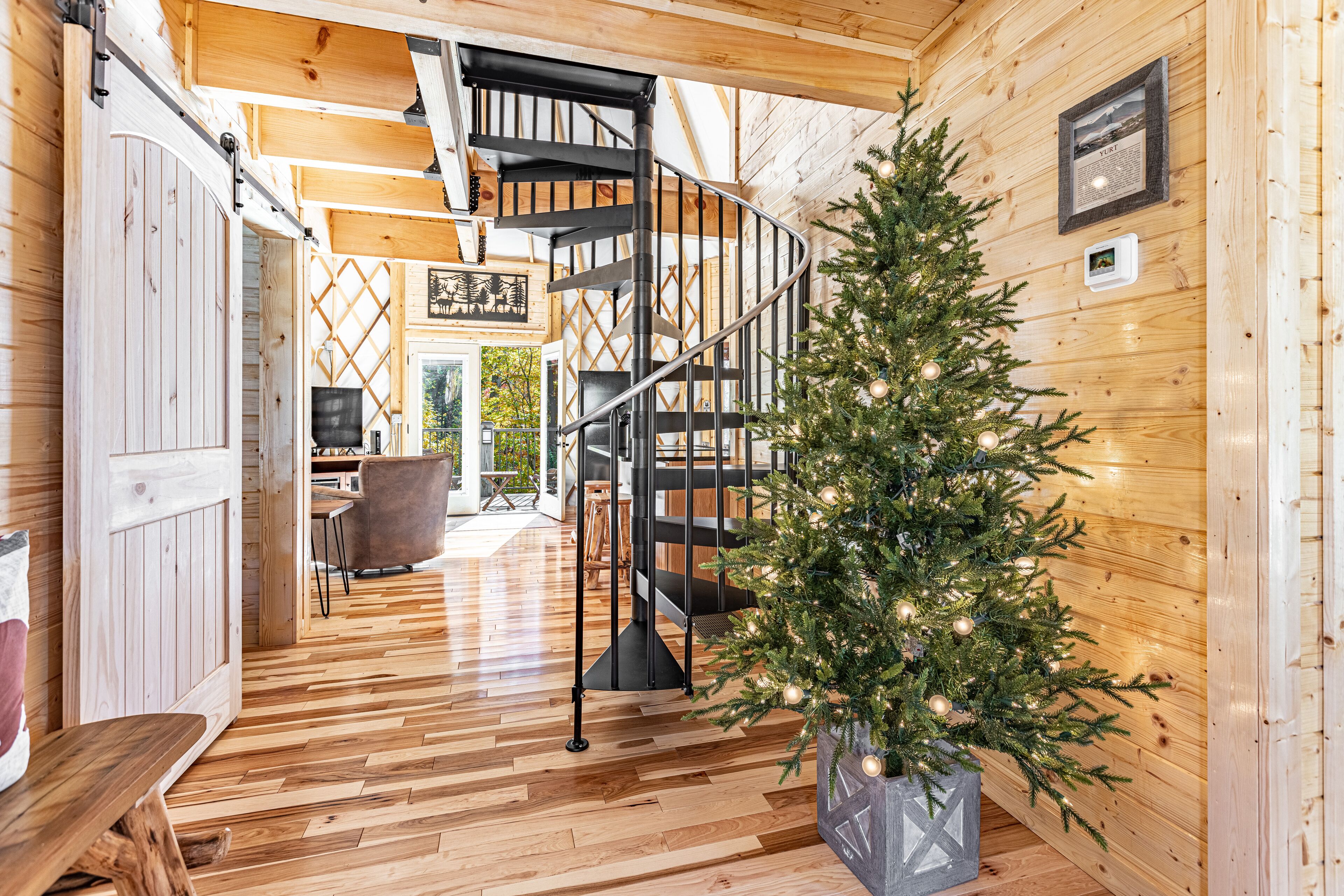Un interno in legno con una scala a chiocciola, un albero di Natale e un'area pranzo.
