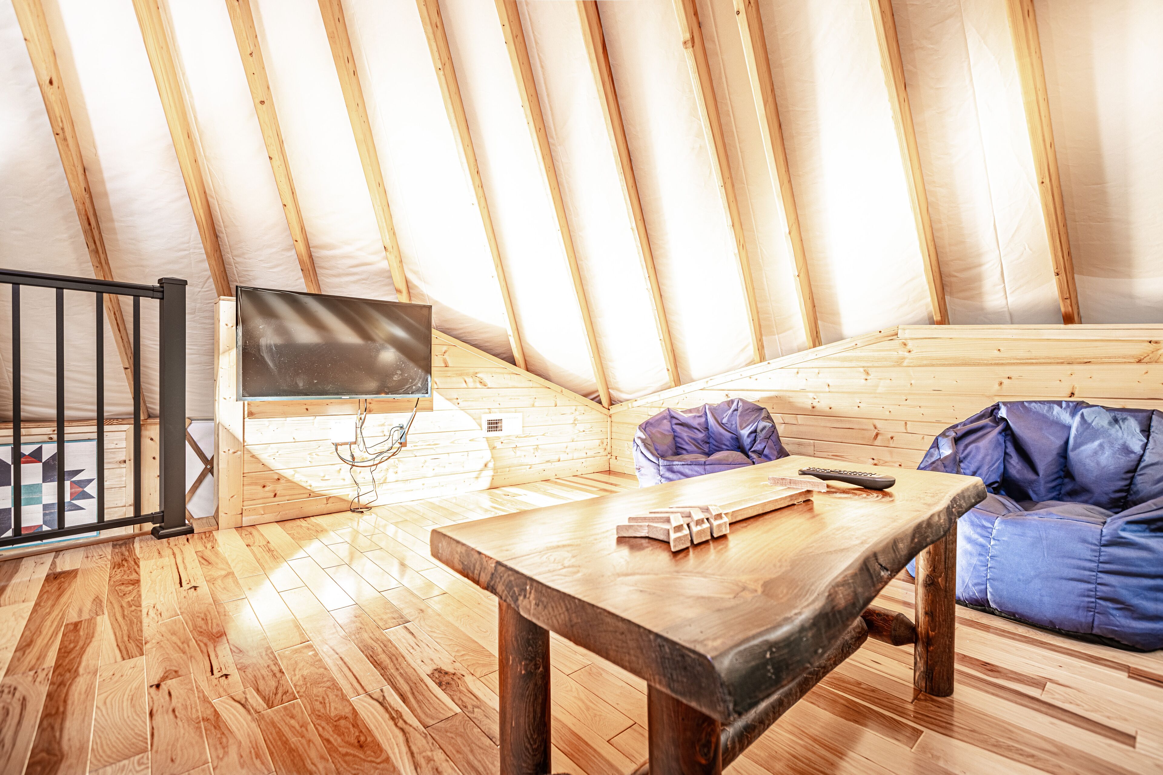 A wooden interior with a table, a sofa, and a TV on a wall.