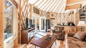 A cozy cabin interior with a wooden interior, a dining area, a sofa, and a kitchen area. - Cozy Blue-Beary great f/ couples or small family, Huge Deck w/Privte Hot Tub (Pigeon Forge)