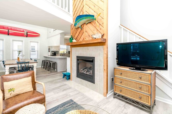 A living room with a fireplace, a television, and a surfboard.
