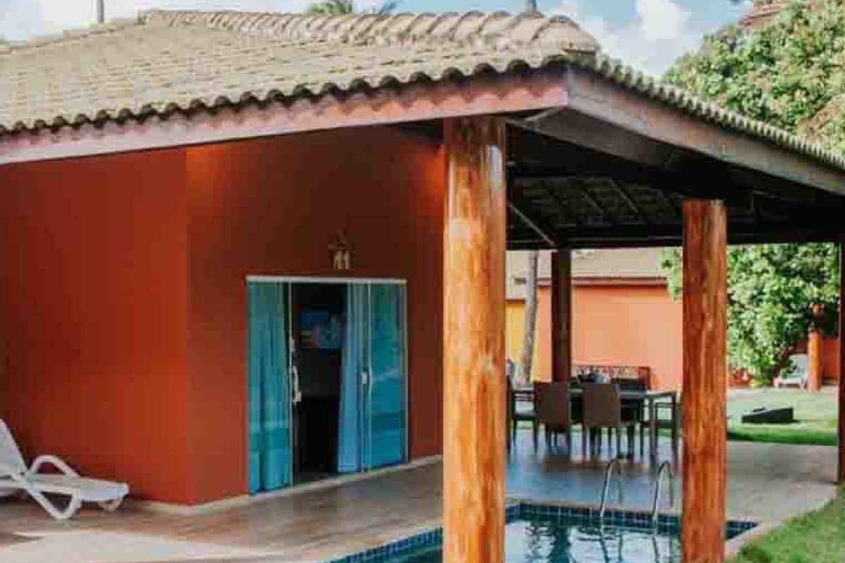 A building with a red exterior, a covered outdoor area with a pool, and a door leading to a covered entrance.