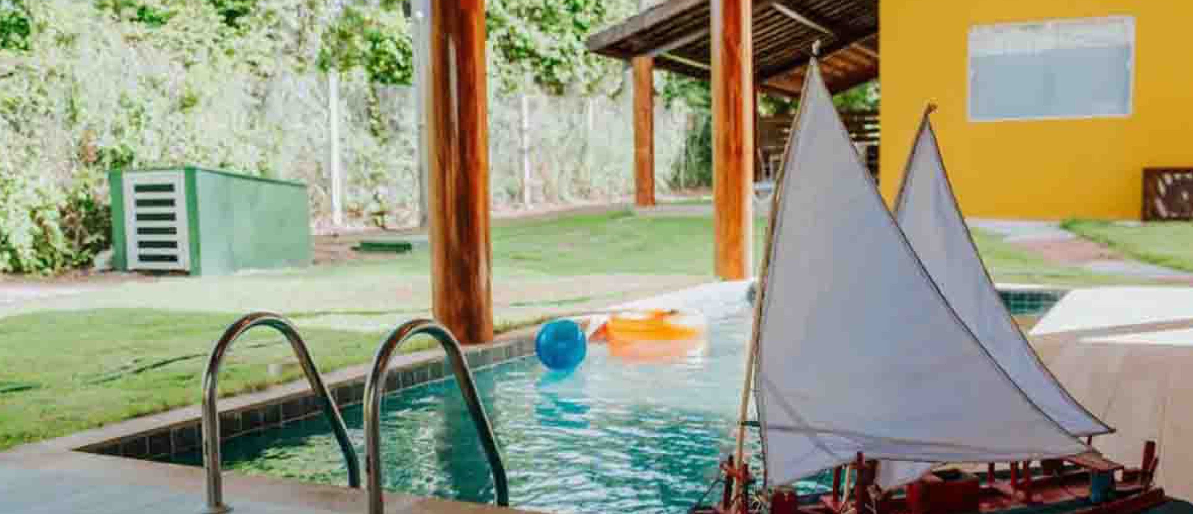 Piscina com modelo de veleiro, escadas de metal e estrutura de deck de madeira.