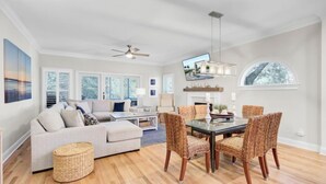 A spacious living room with a sofa, coffee table, and dining area with chairs. - Award-Winning Resort Amenities | Grand Pavilion 09 (Isle of Palms)