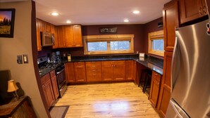 Una cocina con armarios de madera, un refrigerador de acero inoxidable y una ventana sobre el lavamanos.