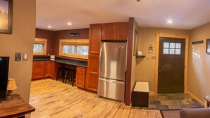 Una cocina con armarios de madera, un refrigerador de acero inoxidable, una ventana y una puerta con una imagen de un oso.