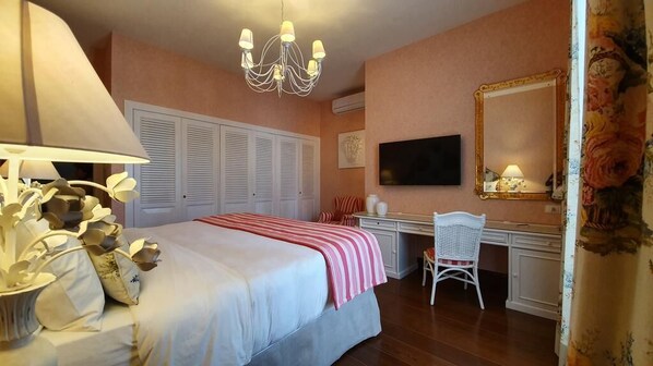A bedroom with a bed, a desk, a chair, a television, and a mirror.