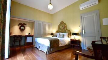 Quarto com cama, mesas de cabeceira, escrivaninha e uma cadeira.