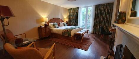 Una habitación de hotel con cama, escritorio, silla, lámpara y chimenea.