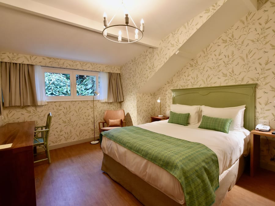 Un dormitorio con una cama grande, un escritorio, una silla, una mesita de noche y una ventana con cortinas.