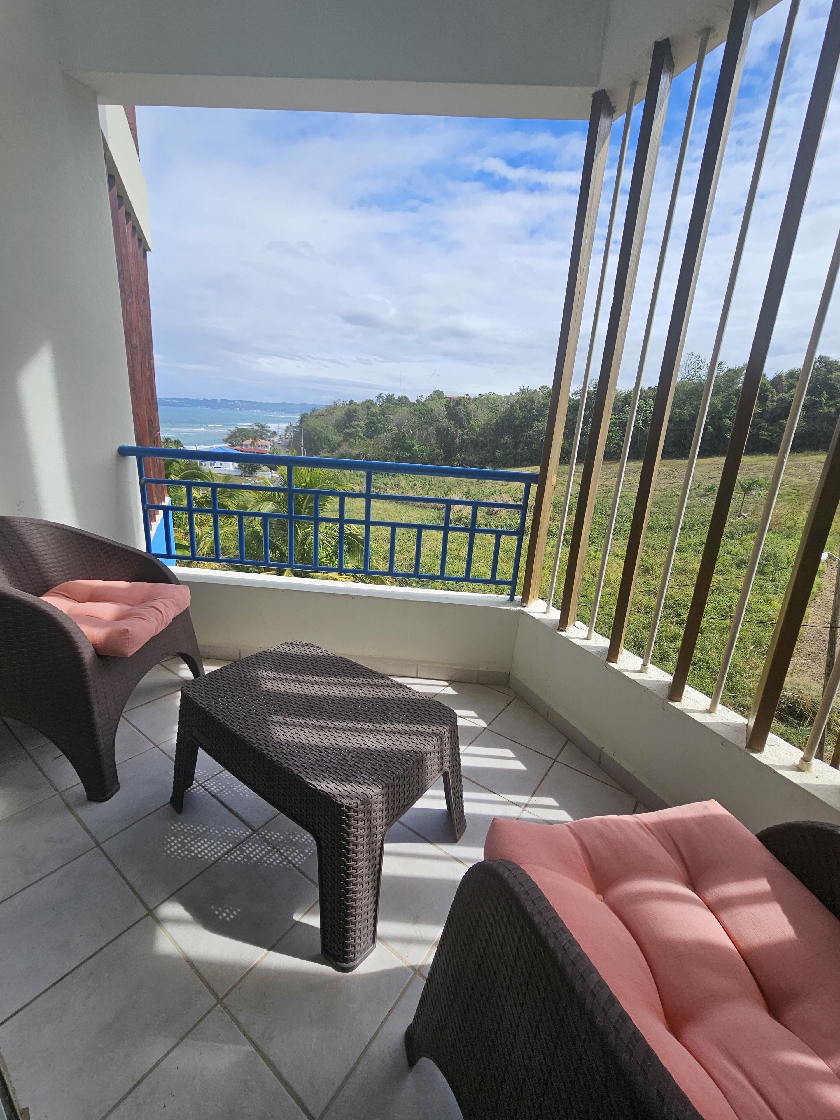 A balcony with wicker furniture and a view of the sea.
