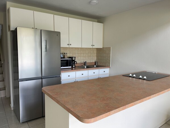 A modern kitchen with a stainless steel refrigerator, a microwave, a coffee maker, and a gas stove.
