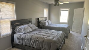 A bedroom with two beds, a ceiling fan, and a door. - Heart of the Loess Hills (Moorhead)