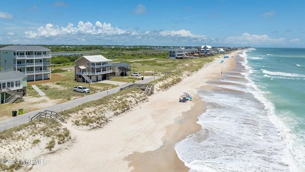 Ein Küsteneigentum mit mehreren Gebäuden, einem Sandstrand und Blick auf den Ozean.