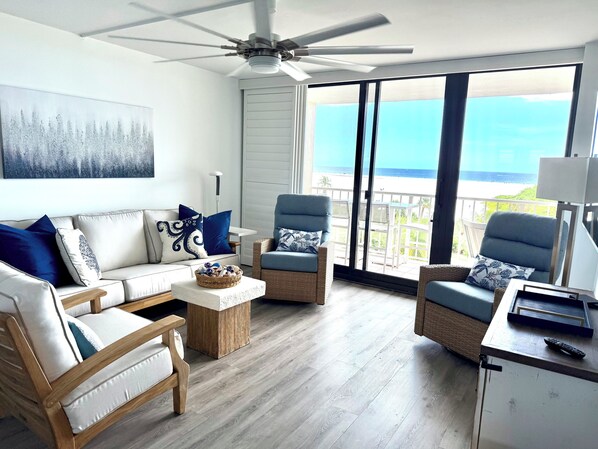 A modern living room with a sofa, two armchairs, a coffee table, and a ceiling fan.